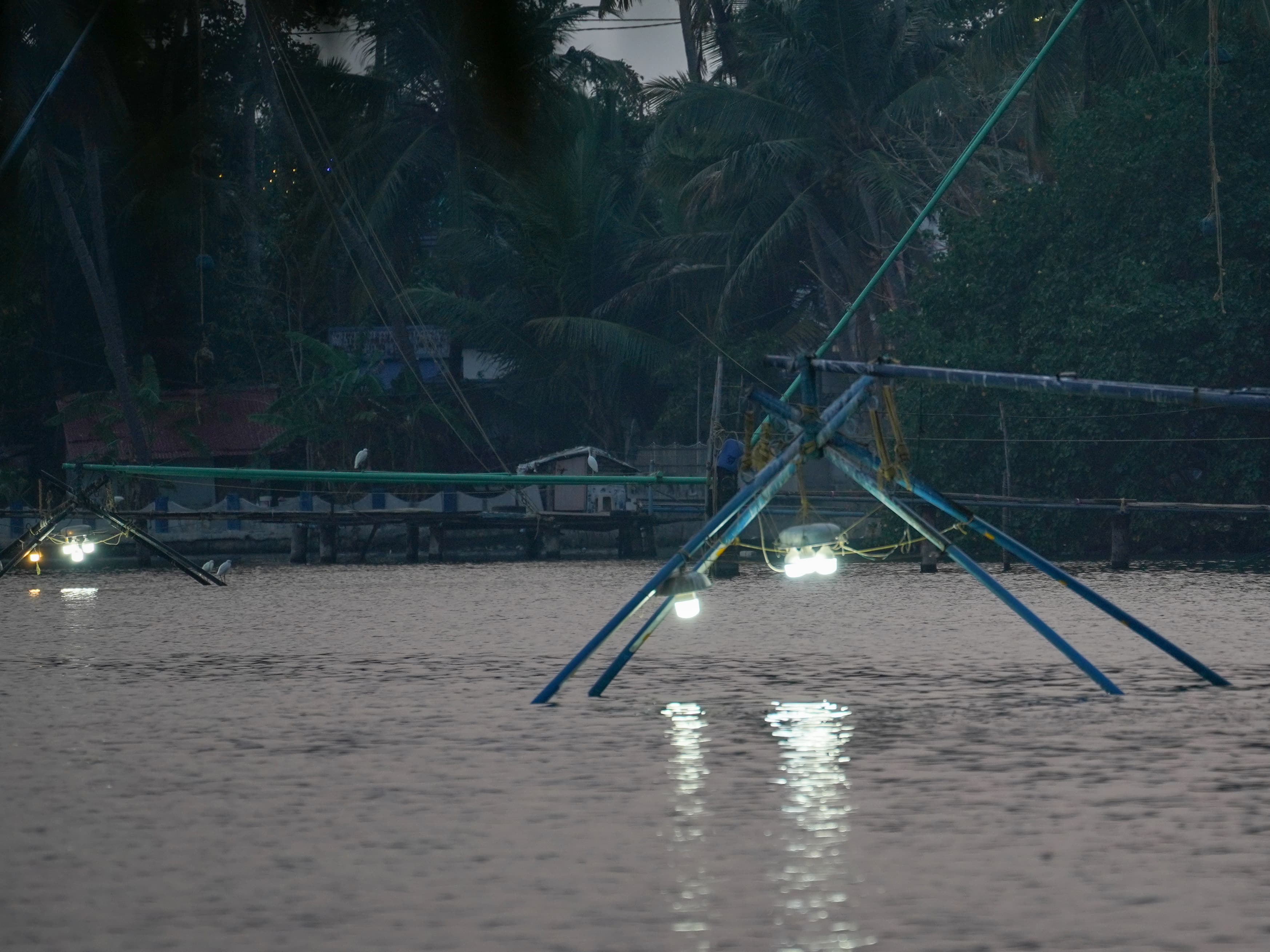Chinese fishing nets lit by lamps over the water at night, Ashtamudi Lake